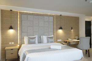 - une chambre avec un grand lit blanc et un bureau dans l'établissement 1O1 URBAN Jakarta Thamrin, à Jakarta
