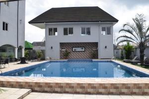 ein Haus mit einem Pool vor einem Haus in der Unterkunft Golden Tulip Hotel -GT31 Stadium Road in Port Harcourt