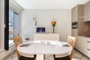 Appartement L'Outa 209 - Happy Rentals في شامونيه مون بلان: مطبخ أبيض مع طاولة بيضاء وكراسي