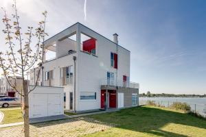 una casa blanca con ventanas rojas y un cuerpo de agua en Ostseewind: Wasserblick, finnische Sauna, Whirlwanne, Kamin, 2 Parkplaetze en Kappeln