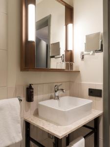 W łazience znajduje się biała umywalka i lustro. w obiekcie Elite Hotel Mårtenson w mieście Halmstad