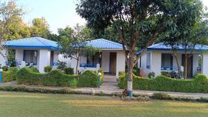 a white house with a blue roof at BENTO CORBETT WOODS RESORT in Jhirna