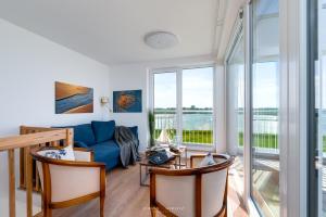 a living room with a blue couch and glass windows at Ferienhaus Nis Randers in Olpenitz