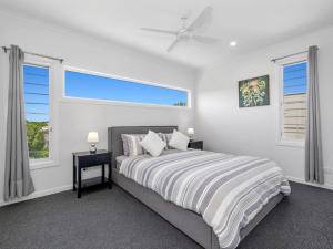 a white bedroom with a bed and two windows at The Beachside Sanctuary -500m from Beach with Pool & Heated Spa in Casuarina +21 photos