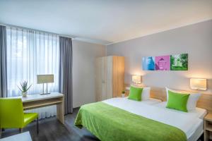 ein Hotelzimmer mit einem grünen Bett und einem Schreibtisch in der Unterkunft Hotel Dusseldorf Krefeld Affiliated by Meliá in Krefeld