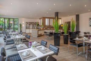 ein Restaurant mit Tischen und Stühlen und eine Küche in der Unterkunft Hotel Dusseldorf Krefeld Affiliated by Meliá in Krefeld