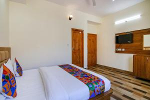 a bedroom with a bed and a flat screen tv at FabHotel Himalayan Park in Bajaura