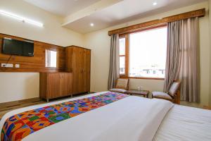 a bedroom with a bed and a flat screen tv at FabHotel Himalayan Park in Bajaura