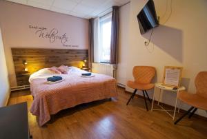 a bedroom with a bed and two chairs and a television at Bed & Breakfast Hotel Het Gerendal in Schin op Geul