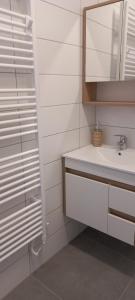 un bagno bianco con lavandino e specchio di Onix-Vital Apartman Orfű a Orfű