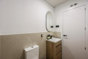 a bathroom with a toilet and a sink and a mirror at Asequible apartamento a pasos de Callao in Madrid