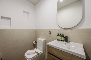 een badkamer met een wastafel, een toilet en een spiegel bij Asequible apartamento a pasos de Callao in Madrid