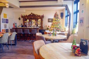 een kerstboom in een restaurant met tafels en stoelen bij Bed & Breakfast Hotel Het Gerendal in Schin op Geul