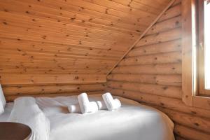 Cozy house on Parnassos Mountain في أراخوفا: سرير أبيض في غرفة بجدار خشبي