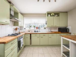 uma cozinha com armários verdes e um fogão forno superior em Pass the Keys Stylish Modern 3 bed house with Parking em Rickmansworth