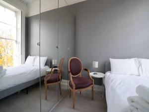 1 dormitorio con 2 camas, 2 sillas y espejo en Pass the Keys Lovely bright and central apartment in Cheltenham en Cheltenham