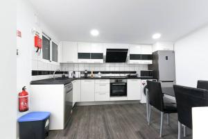 a kitchen with white cabinets and black appliances at Casa do Sol in Funchal