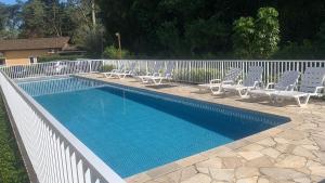 a swimming pool with lounge chairs and a fence at Casa Condomínio Juquehy 100 M do Centrinho in Juquei