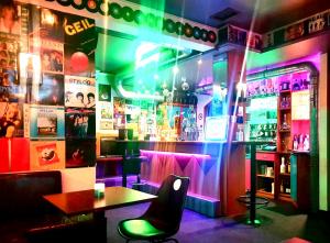 een bar met een tafel en stoelen en neonlichten bij Hotel am Bahnhof in Feldkirch