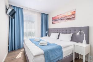 a bedroom with a large bed with blue curtains at Perfect Holiday Apartments Bel Mare by Renters in Międzyzdroje