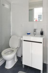 a white bathroom with a toilet and a sink at Casa do Mar in Funchal
