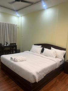 a bedroom with a large bed with white sheets and pillows at Athirappilly Inn in Athirappilly