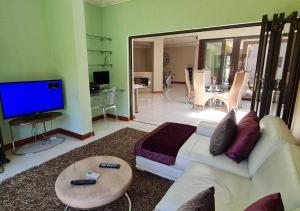 a living room with a white couch and a tv at 10 Pecanwood Dr 4 Bedroom Beauty in Hartbeespoort
