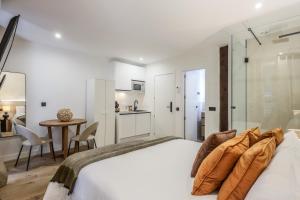 a white bedroom with a bed and a table at Estudio funcional Plaza del Callao in Madrid