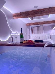 - une piscine avec une bouteille de bière et des verres à vin dans l'établissement À la folie - Loft & Spa, à Montrevault