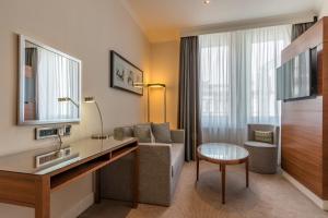 a hotel room with a desk and a couch and a chair at Thistle London Piccadilly in London