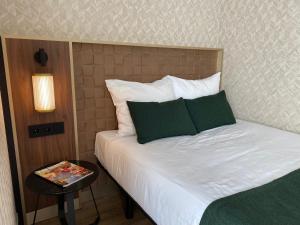 Schlafzimmer mit einem Bett mit weißer Bettwäsche und grünen Kissen in der Unterkunft Two Brothers Noordwijk Beach in Noordwijk aan Zee