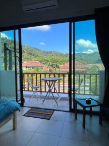 a room with a balcony with a table and a view at Petunya Phuket Guest House in Ban Huai Luk (1)