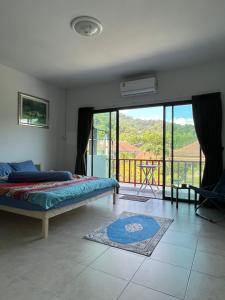 a bedroom with a bed and a balcony with a view at Petunya Phuket Guest House in Ban Huai Luk (1)