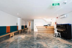 an empty waiting room with a piano and benches at Haven Hut Riverside Hotel in Ho Chi Minh City