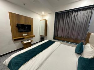 a bedroom with a bed and a flat screen tv at Hotel secure inn saroli in Surat