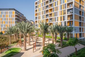 un complejo de apartamentos con palmeras y un parque infantil en Tamm - Mesk 1 Tower en Dubái