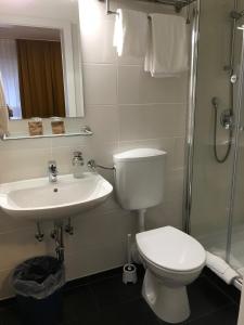 La salle de bains est pourvue de toilettes, d'un lavabo et d'une douche. dans l'établissement Abendruhe Hotel - kontaktloser Check In, à Oberhaching