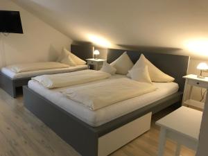 a bedroom with two beds with white pillows at Abendruhe Hotel - kontaktloser Check In in Oberhaching