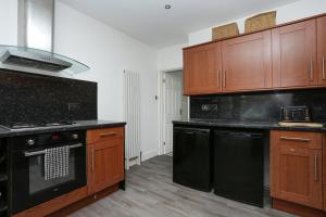 uma cozinha com electrodomésticos pretos e armários de madeira em Secret Seaside Retreat em Kent