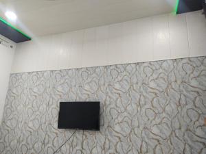 uma televisão de ecrã plano numa parede num quarto em KK PALACE HOMESTAY AND GARDEN em Kota