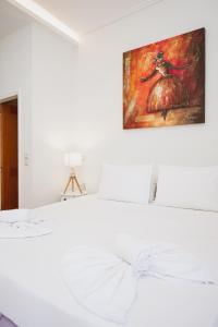 a white bedroom with a painting on the wall at Jenny Apartments in Zakynthos Town