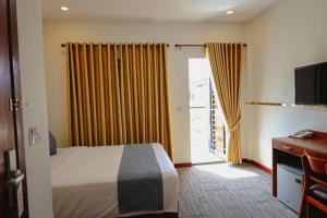 Nimith Hotel & Restaurant في بنوم بنه: غرفة فندق بسرير وباب زجاجي منزلق