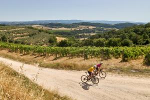 Ein Mann, der ein Fahrrad auf einer unbefestigten Straße reitet in der Unterkunft Hotel & Restaurant Casolare Le Terre Rosse in San Gimignano