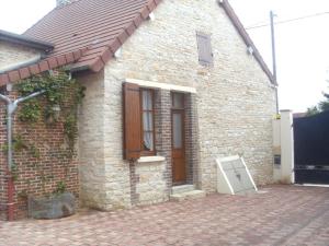 a brick house with a door and a refrigerator outside at Le village in Polisy