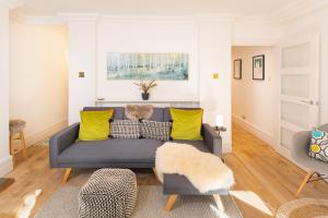 sala de estar con sofá azul y almohadas amarillas en Idyllic Clifton Hideaway - Stunning Garden Flat en Bristol