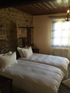 um quarto com 2 camas com lençóis brancos e uma janela em Varosi 4 Seasons em Édessa