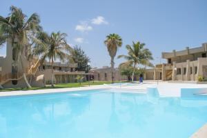 une grande piscine en face d'un bâtiment avec des palmiers dans l'établissement Oasis Praiamar, à Praia