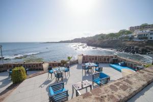 een patio met stoelen en tafels en uitzicht op de oceaan bij Oasis Praiamar in Praia