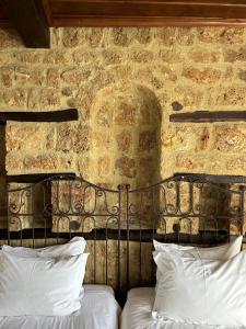- un mur en pierre derrière un lit avec des oreillers blancs dans l'établissement Varosi 4 Seasons, à Édessa