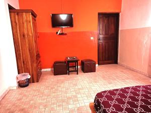 sypialnia z pomarańczowymi ścianami, łóżkiem i telewizorem w obiekcie Cloud9 Lomé w mieście Lomé